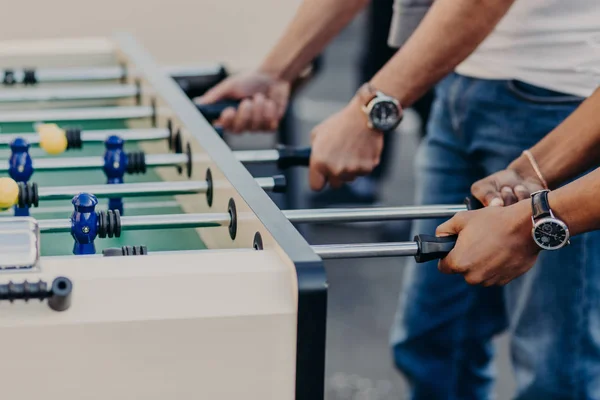 Table football game or soccer. Men play kricker together during weekend as have spare time, enjoy recreation time. Heated people.