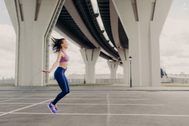 Kardiyo eğitim kavramı. İp, spor giyim, giyinmiş saygısız ile atletik kadın atlar vardır açık havada, egzersizleri, egzersiz sağlıklı vücut, sahip olduğunu düşünen loose ağırlık için kararlı çalışır. Beden eğitimi