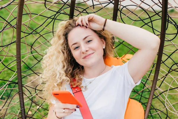 Beautiful Delighted Female Blogger Curly Light Hair Uses Smart Phone — Stock Photo, Image