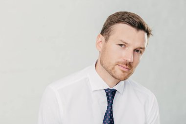 Kendine güvenen erkek ciddi kameraya benziyor, koyu renk gözleri ve anız, kravat, beyaz arka plan üzerinde izole ile zarif beyaz gömlek giymiş vardır. Dostum Yönetmen düşünüyor hakkında nasıl hayatta başarıya ulaşmak