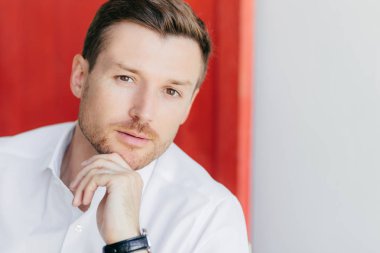 Kendini erkek beyaz gömlek giymiş çene, sağlıklı cilt, muhatap, dinlemek hazır olan tutar emin beyaz ve kırmızı bir arka plana dayanır, reklam veya promosyon için boş alan ile poz veriyor