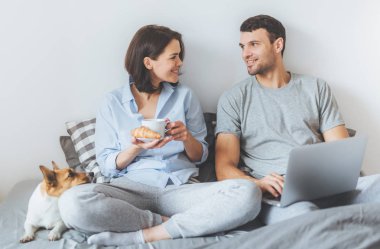 Güzel çift portresi birlikte yatağa otur, dizüstü bilgisayar kullanarak, arada her diğer hoş sohbet, online alışveriş yapmak. Ana yatak odasında yakınındaki kriko Rusya korkunç yatıyor
