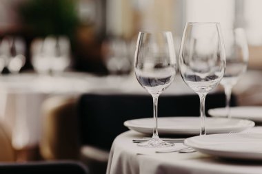Rahat restoran tablo ayarını boş şarap gözlük, beyaz plakalı arka plan bulanık karşı. Şenlikli bir şekilde dekore edilmiş tablo ile ziyafet salonu. Festival olay
