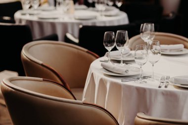 Yatay bir kadeh beyaz kağıt, kadehlerin, tabak, çatal ve bıçaklar, yakınındaki iki koltuk ile servis yuvarlak masa. Lüks restoran rahat ortamda.
