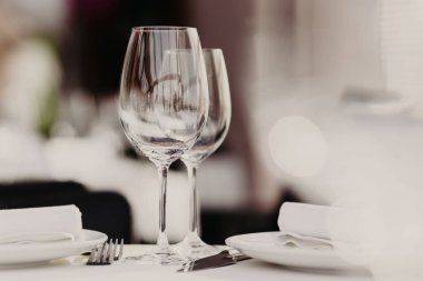Boş gözlük stand tabak ve çatal ziyafet masada yakınındaki beyaz tablewear ile dekore edilmiştir. Festively tablo lokantada arka plan bulanık karşı hizmet