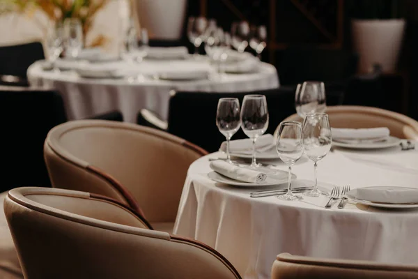 Table served for luxury dinner party with napkins, glasses and plates on white tableclothes. Nice decor. Wedding banquet. Cozy atmosphere in restaurant