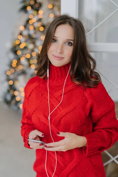 수직의 즐거운 느슨한 따뜻한 스웨터를 모델을 스마트 전화를 이어폰을 인테리어 — 스톡 사진