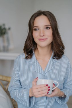 Büyüleyici bak, çizgili pijama giymiş olan rüya gibi Avrupa kadın kapalı atış kahve içer, bir şey hakkında düşünüyor, sakin iç atmosferi sahiptir. İnsanlar, içme ve ev kavramı