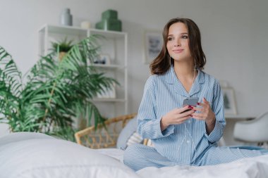 Dalgın büyüleyici Avrupa kadın app için müzik dinleme kullanır, ses kulaklık, bağlı yüksek hız internet, geçirdiği hafta sonu evde güzel sahiptir. Modern teknolojiler ve yaşam tarzı kavramı