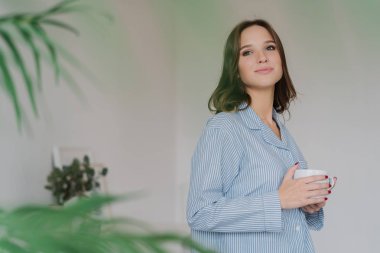 Rüya gibi beyaz bir kadın giyinmiş rahat kıyafetler, İçecek çay, yana doğru kadeh iç iç kopya alanı için reklam içeriğinizi ile karşı kapalı duruyor. Kişi, dinlenme ve içme kavramı