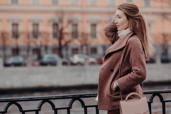 Bfashionable 美丽的女人穿着时尚的大衣 保持手在口袋里 集中到距离 有走在城市 思考的东西 有良好的休息 人与生活方式概念 — 图库照片
