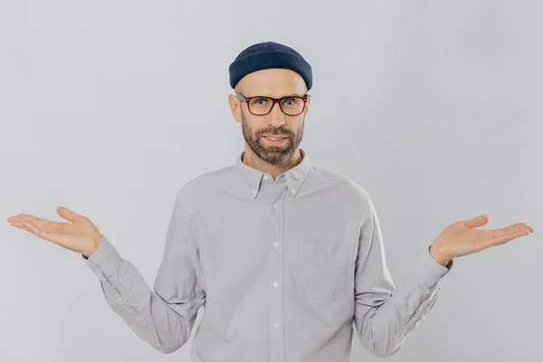 Photo Handsome Man Uncertain Expression Spreads Hands Wears Glasses Headgear — Stock Photo, Image