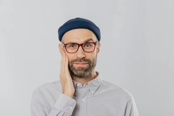 Blue Eyed Unshaven Man Raises Eyebrow Keeps Hand Cheek Looks — Stock Photo, Image