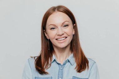 Gülümsüyor koyu düz saçlı çekici genç kadın fotoğrafı ne mutlu ki, kot gömlek giymiş, beyaz arka plan üzerinde pozlar ifade eder olumlu duygular, modelleri kapalı. İnsanlar, Güzellik, yaşam biçimi