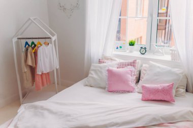 Büyük yatak, elbise askıları, beyaz perdeler ile pencere ile boş rahat ferah yatak odası fotoğraf. Aile içi atmosfer. Kapalı atış