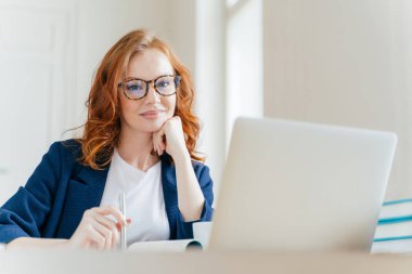 Yatay atış hoş görünümlü başarılı profesyonel kadın avukat istemcileri durumda öğrenir, modern dizüstü bilgisayar, giymiş resmi giyim ve şeffaf gözlük çalışır, ofiste pozlar