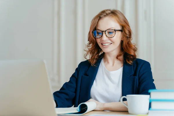 Glad Lovely Woman Has Ginger Hair Positive Smile Sits Laptop — Stock Photo, Image