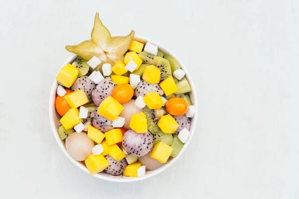 Pemandangan atas buah eksotis segar dalam mangkuk. Potongan buah naga putih, kiwi, pitaya, mangga dan buah bintang. Makanan penutup vegetarian lezat untuk dimakan — Stok Foto