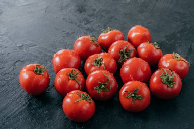 Yeşil yaprakları ile Heilroom taze kırmızı domates, su damlaları, koyu arka plan üzerinde izole. Bahçeden hasat edilen lezzetli olgun sebzeler