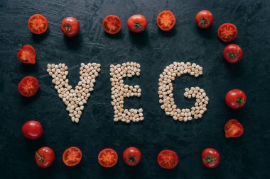 Gıda ve beslenme konsepti. Veganlar için ürünleri ifade eden veg harfi şeklinde kuru garbanzo yatay çekim. Domates çerçeve etrafında