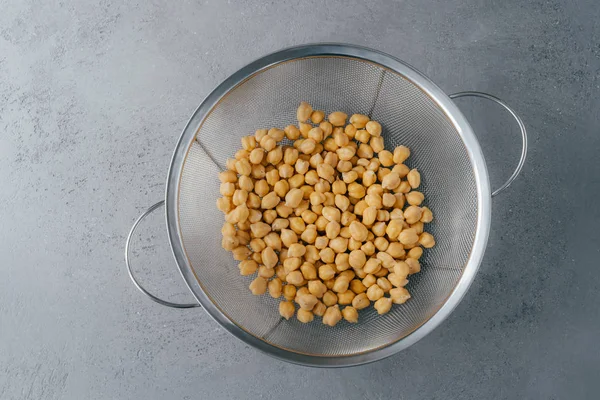 Overhead view of chickpeas in sieve against grey background. Legumes for vegans. Organic dish. Healthy eating concept. Vegetarianism — Stock Photo, Image