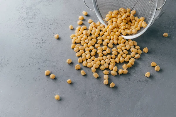 Boiled chickpeas spill out from sieve. Garbanzo grains. Eco product. Dry peas. Copy space. Nut seeds. Organic food. Vegan ingredient — Stock Photo, Image