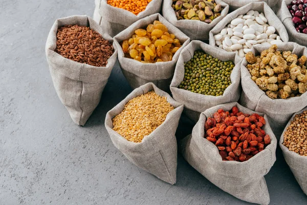 Dieta, nutrición y concepto de alimentación saludable. Cereales coloridos y frutas secas ricas en proteínas en sacos de arpillera. Semillas de legumbres secas . — Foto de Stock