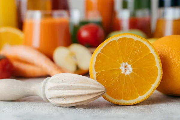 Cortado naranja fresca con exprimidor. Hacer jugo de fruta fresca. Color naranja. Frascos borrosos de jugo en el fondo. Disparo horizontal —  Fotos de Stock