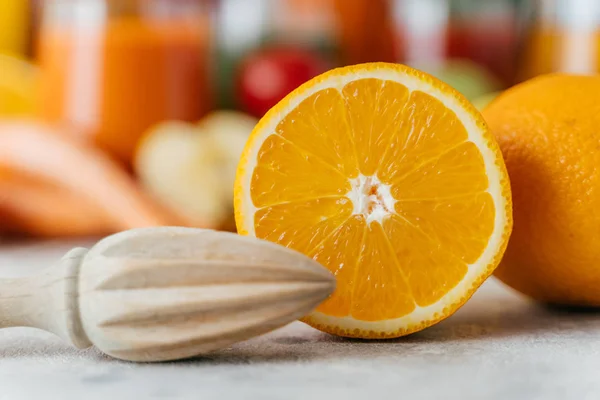 Primer plano del exprimidor de madera y naranja fresca en rodajas. Cítricos jugosos sobre fondo borroso. Enfoque selectivo. Concepto de alimentación saludable —  Fotos de Stock