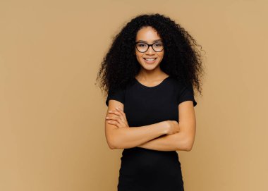 Afro saç kesimi ile Ince memnun kadın, siyah rahat bez giyer