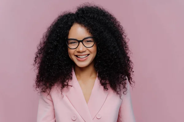 Gros plan portrait de heureuse femme aux cheveux bouclés a doux sourire sur le visage, peau sombre et saine cheveux touffus, porte des vêtements élégants, isolé sur fond violet, aime venir week-end, travaille au bureau — Photo