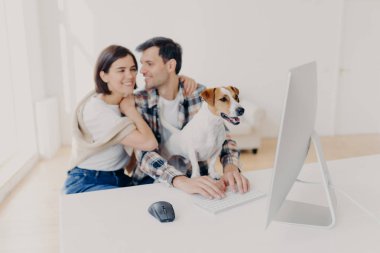 Sevecen çift kucaklaşacak ve öpüşecek modern bilgisayarda romantik bir film izleyecek, soylu köpek ilgiyle monitöre odaklanacak. Hoş bir aile, ev ortamında boş zaman geçirir.