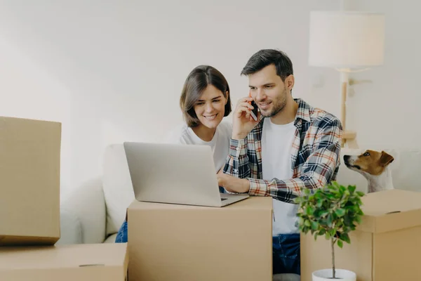 Hombre Feliz Navega Portátil Nuevo Piso Llamadas Través Teléfono Inteligente —  Fotos de Stock