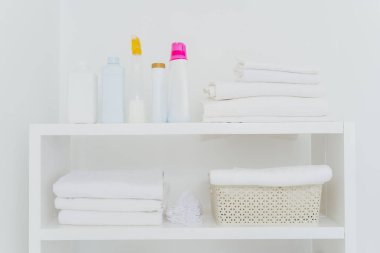 Temiz katlanmış havluları, bir şişe sıvı yıkaması ya da deterjanı olan çamaşır odası. Her şey beyaz renkli. Günlük ev işleri ve çamaşır günü.