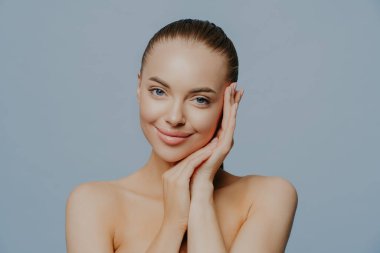 Güzel kadın portresi. Mavi arka planda mükemmel taze cilde sahip güzel bir spa mankeni kız. Esmer kadın kameraya bakıyor. Gençlik ve cilt bakımı kavramı.