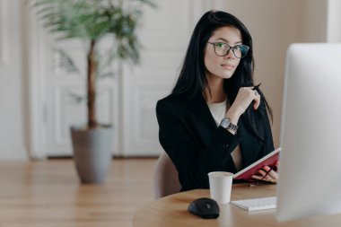 Ciddi bir kadının resmi deftere bilgi yazar, yeni online iş kursları öğrenir, bilgisayarla birlikte poz verir, proje üzerinde çalışır, bazı fikirler yazar. İş ve iş kavramı