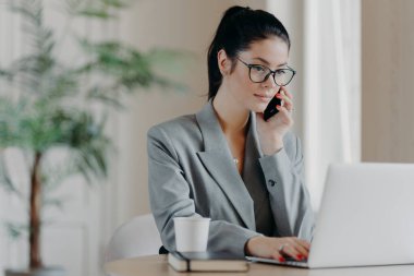 Ciddi esmer kadın klavye bilgisi, dizüstü bilgisayara odaklanmış, resmi kıyafetler giymiş, ortak çalışma alanında poz veriyor, gündüz çalışma sürecinde uzaktan çalışıyor..