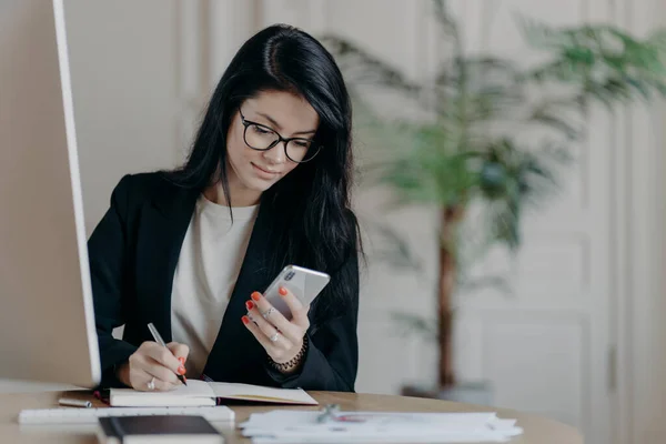 Allvarligt Snygg Vuxen Kvinna Med Mörkt Hår Koncentrerad Till Mobiltelefon — Stockfoto