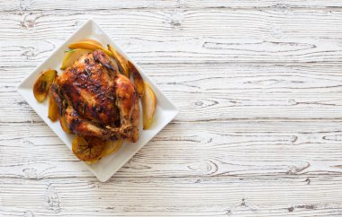 Elma ve armut beyaz ahşap zemin üzerinde beyaz tabakta tavuk kızarmış. Düz yatıyordu. Kopya alanı