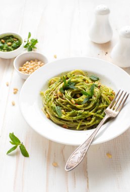 Fesleğenli İtalyan makarnası ve beyaz tabakta ıspanak pesto. 