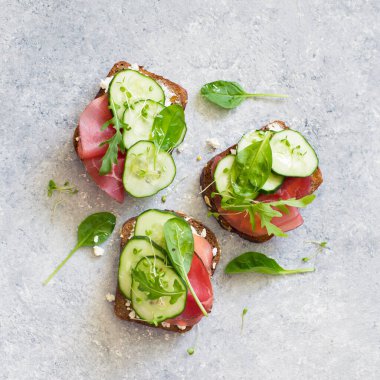 Taze sebzeli, jambonlu ve yumuşak peynirli gri taştan arkaplanlı sağlıklı açık sandviçler. Düz yatıyordu. Sağlıklı diyet kavramı