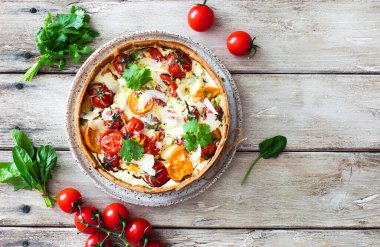 Doğal ahşap masada ev yapımı domates ve ıspanaklı turta (quiche). Düz yatıyordu. Boşluğu kopyala