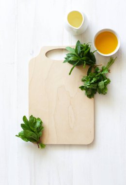 Boş tahta kesme tahtası, taze yeşiller, zeytinyağı ve limon suyu. Yemek arkaplanı. Sağlıklı gıda konsepti