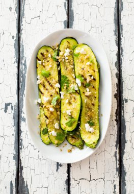 Eski ahşap arka planda ızgara kabak dilimleri ve beyaz tabakta ceviz. Düz yatıyordu