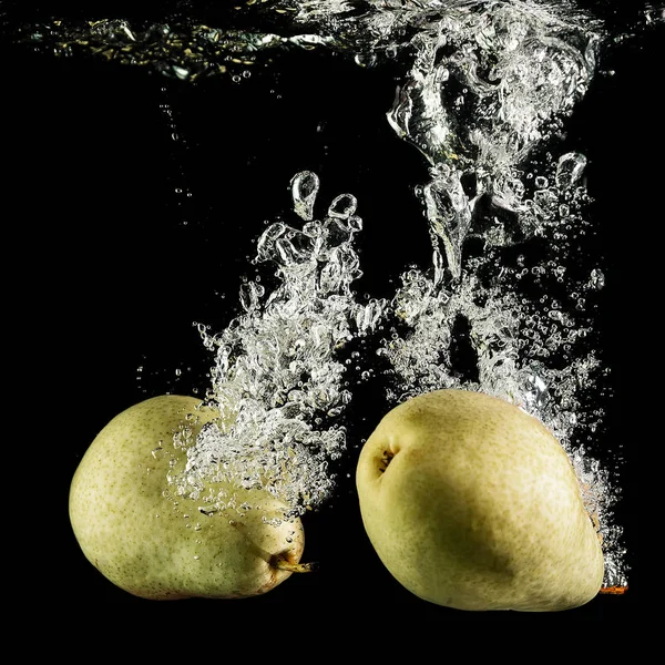Two pears in water on black background