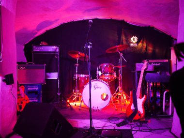 Stage with a microphone and a drum set. The drum set is made by Gretsch