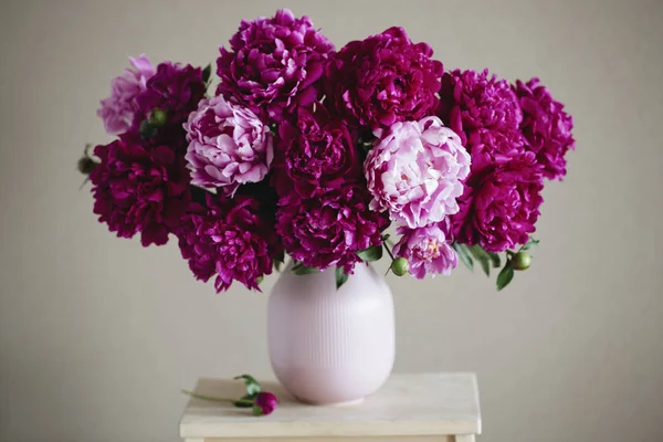 Koyu pembe peonies bir vazo içinde. Natürmort. Kahverengi zemin