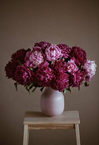 Koyu pembe peonies bir vazo içinde. Natürmort. Kahverengi zemin