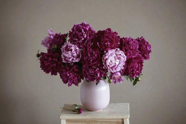 Koyu pembe peonies bir vazo içinde. Natürmort. Kahverengi zemin