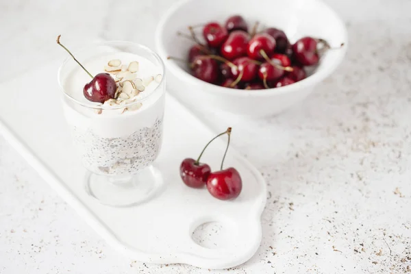 yogurt with chia seeds, oatmeal and cherries on a light background